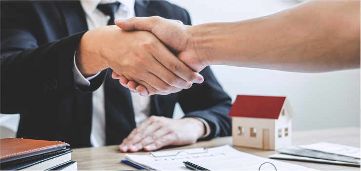 Two people shaking hands over Contract Paperwork