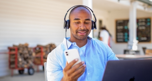Man looking at phone with headphones on