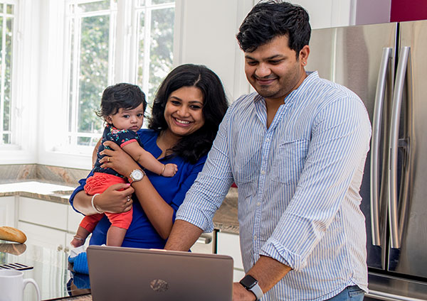 Man woman and baby in kitchen on computer