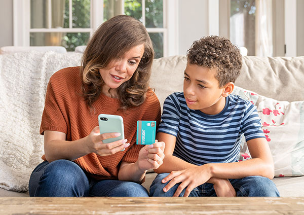 Mother showing son Greenlight app on phone, holding card