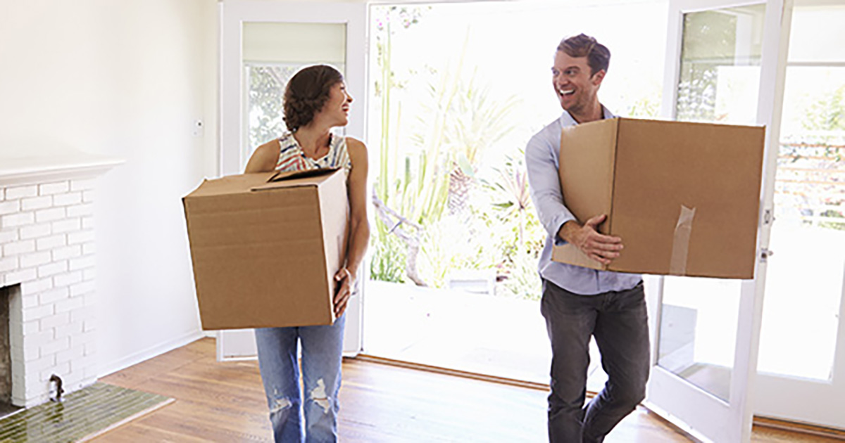 Couple moving boxes into new home