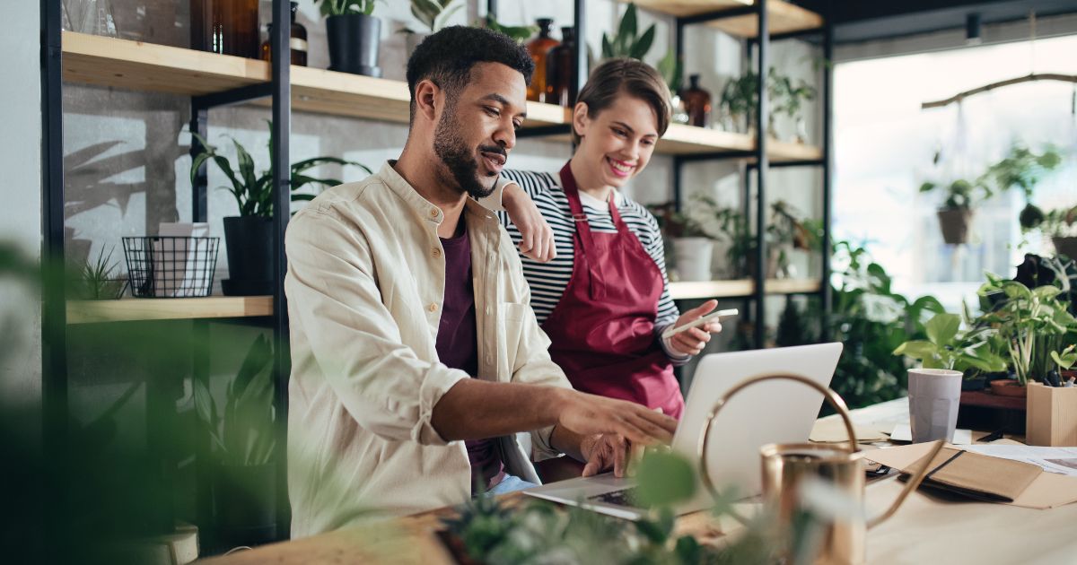 Man and woman business owners in a plant shop looking at a laptop.