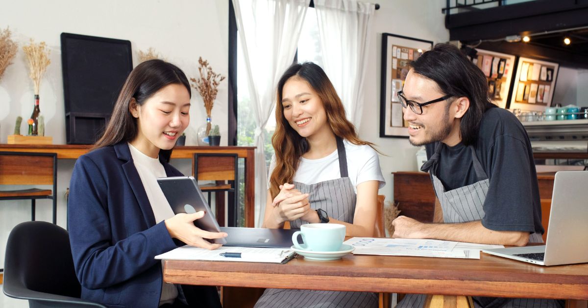 Two coffee shop owners speaking with a financial advisor over coffee