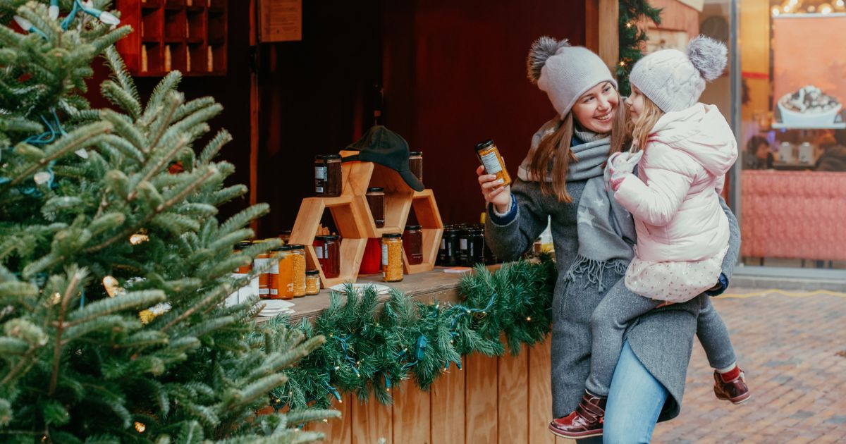 Mother holding young daughter while shopping at a winter market