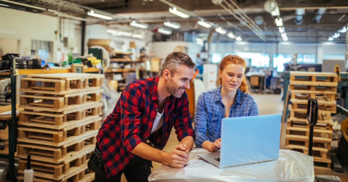 Woman and man using laptop in warehouse