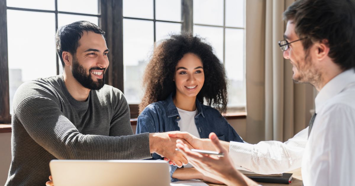 Smiling woman and man shaking hands with an advisor