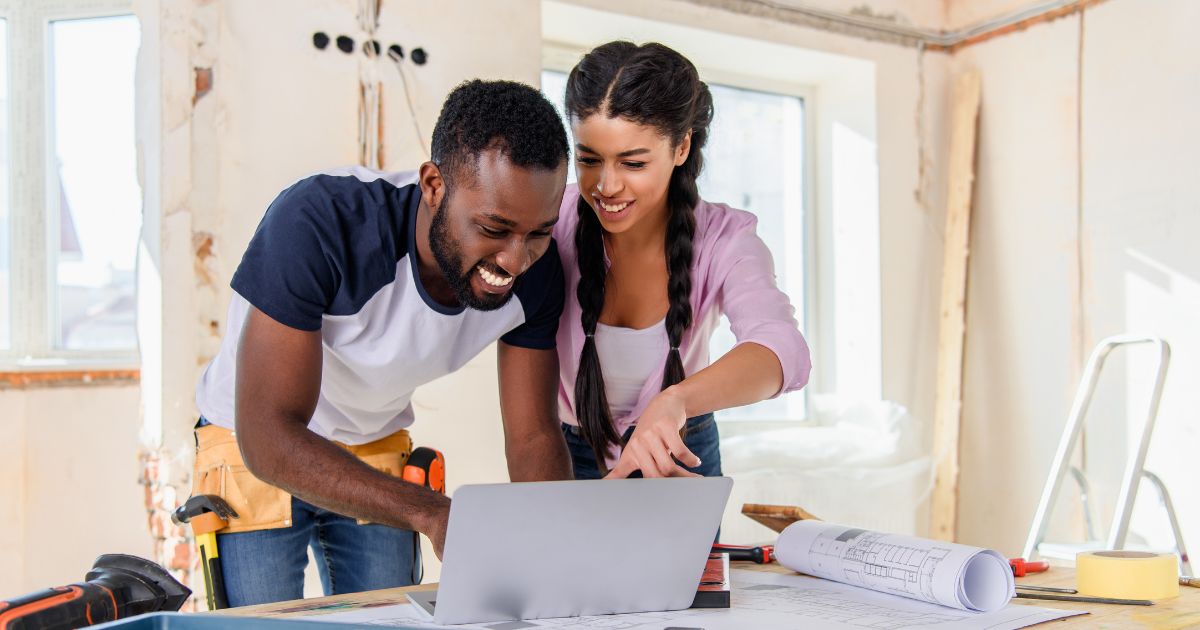 Couple in the middle of a home renovation looking at a laptop.