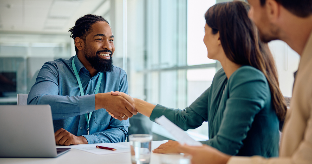 Loan officer shaking hands with woman client at table