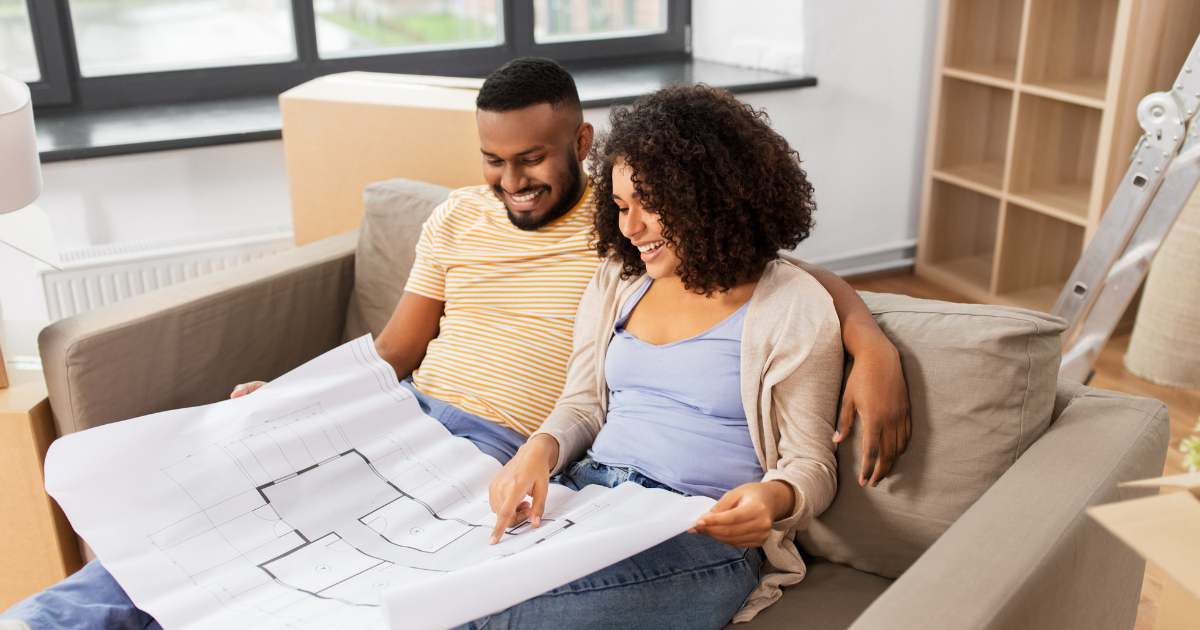 Couple sitting on couch reviewing home build blueprint